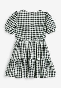 Robe à carreaux noirs et blancs avec manches courtes bouffantes, jupe à volants et fermeture éclair au dos. Fabriquée en coton léger.