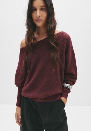 Bordeaux, übergroßer Strickpullover mit schulterfreiem Design und gerippten Bündchen. Verfügt über eine strukturierte Oberfläche und verzierte Armstulpen.