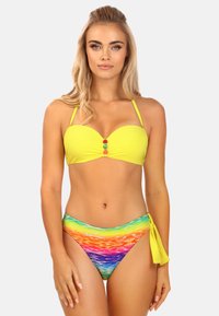 Żółty biustonosz bikini z trzema kolorowymi koralikami na środku, w połączeniu z wysokim bikini z dołami w wielokolorowy falisty wzór.