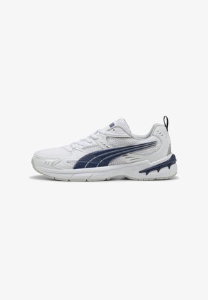 Zapatilla deportiva blanca con acentos en azul marino, parte superior de malla y superposiciones texturizadas. Cuenta con una suela acolchada y una pestaña de talón resistente para mayor soporte.