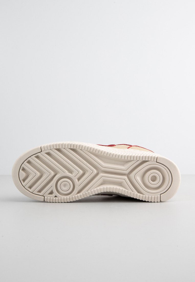 Suola di scarpa in materiale gommoso testurizzato, caratterizzata da un grip a motivo, colore beige pallido e indentazioni circolari per la trazione.