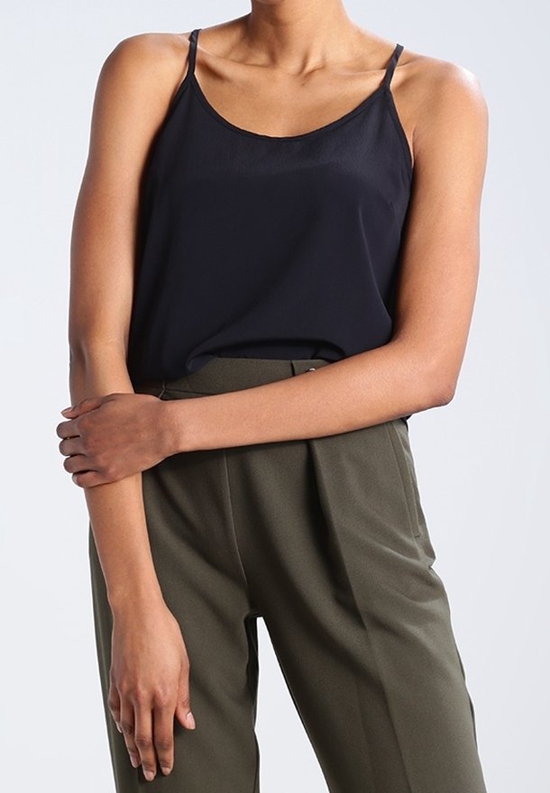 Ciemnoniebieski top bez rękawów z cienkimi ramiączkami, wykonany z gładkiego materiału. Noszony z wysokim stanem oliwkowymi spodniami z zakładkami.