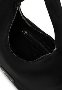 Μαύρη τσάντα χειρός με απαλό, ματ φινίρισμα, εσωτερική τσέπη με φερμουάρ και μαλακή, στρογγυλή μορφή. Περιλαμβάνει δερμάτινη ετικέτα με επωνυμία.