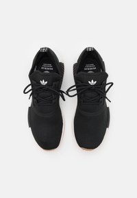 Zapatillas deportivas negras con parte superior de punto texturizado, diseño de cordones, logo blanco en la lengüeta y suela de goma.