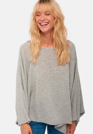 Pull en tricot côtelé gris clair avec des manches larges et une coupe lâche. Présente un col bateau et un design texturé, associé à du denim.