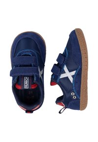 Zapatillas azul marino hechas de material sintético con correas de velcro grises, suelas de goma y un acento blanco en forma de X en los laterales.