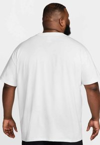 White cotton t-shirt with short sleeves, a crew neckline, and a relaxed fit, shown from the back, featuring smooth, even texture.