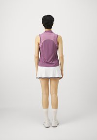 Purple sleeveless athletic top with a curved back seam, paired with a white skirt featuring a black trim and white ankle socks.
