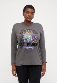 Grå långärmad t-shirt med rund hals. Grafisk design med en leopard och text i varierande färger, vilket skapar en djärv visuell kontrast.