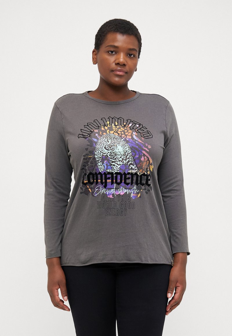 Grå långärmad t-shirt med rund hals. Grafisk design med en leopard och text i varierande färger, vilket skapar en djärv visuell kontrast.