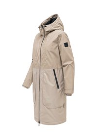 Lang beige hettejakke med svart glidelås, glidelåslommer på sidene og elastiske mansjetter på hvit bakgrunn.