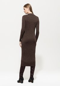 Braunes, langärmliges Strickkleid mit tailliertem Schnitt, versehen mit metallischen Glitzerpartikeln. Mit Kragen und fällt unter das Knie.