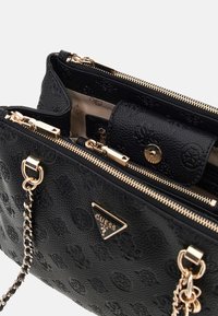 Borsa nera testurizzata con hardware dorato, compartimenti con doppia cerniera e motivo logo in rilievo. Presenta una tracolla a catena per versatilità.