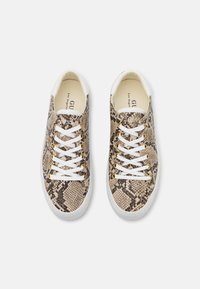 Sneakers with a snake print pattern in tan and brown, featuring white laces, gold eyelets, and a white rubber sole.