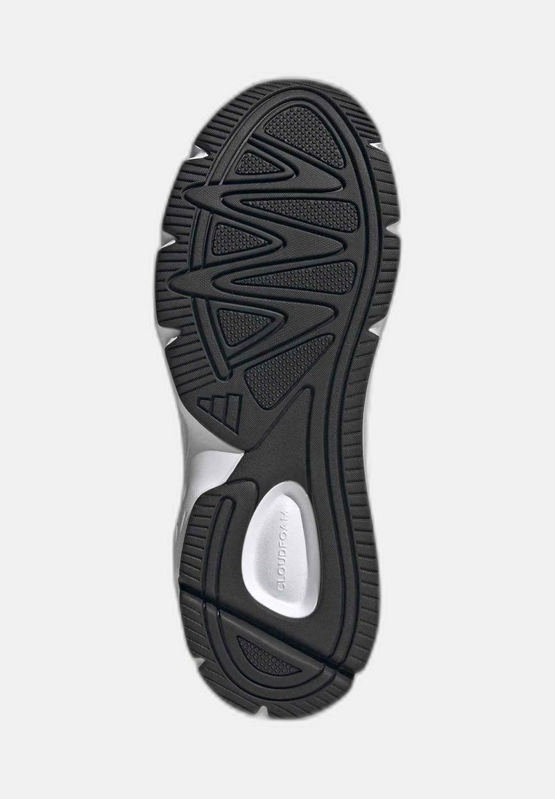 Black rubber shoe sole with textured grip patterns, zigzag indents, and a silver detail near the heel. Durable, designed for traction.