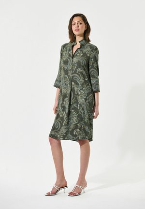 Green patterned dress with long sleeves, button-up design, and a knee-length cut. Features decorative cuffs and subtle floral motifs.