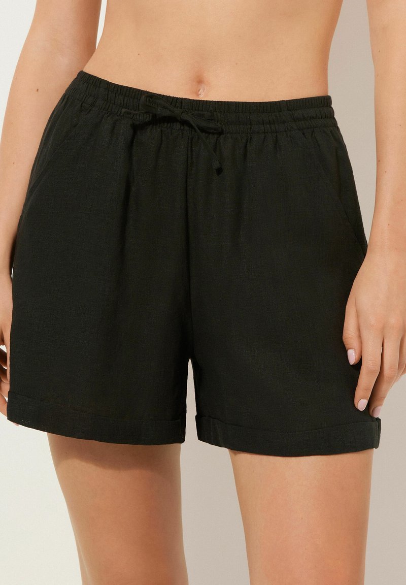 Sorte, letvægts shorts lavet af tekstureret stof. Har en elastisk talje med snøre, sidelommer og opfoldede kanter.