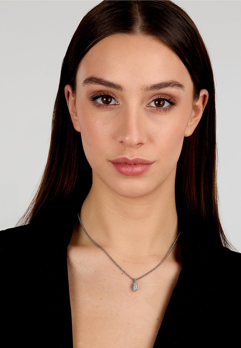 Collana d'argento con un pendente a forma di goccia adornato da pietre scintillanti, appeso a una catena delicata.