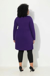 Lila, langärmliges Kleid mit strukturiertem Muster, tailliert, kombiniert mit schwarzen Leggings und High Heels, von hinten betrachtet.