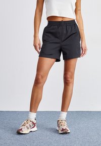 Pantalones cortos deportivos negros con una cintura elástica, combinados con zapatillas multicolores con parte superior de malla y suela de goma.