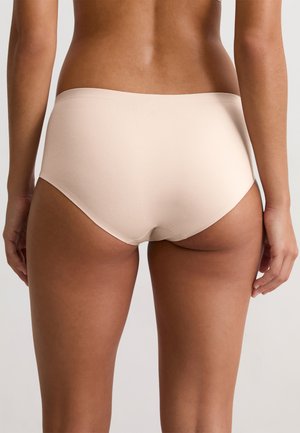 Woman wearing light beige seamless underwear, shown from the back, standing against a plain white background.