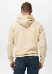 Beige hætte sweatshirt med en blød tekstur, lange ærmer og en afslappet pasform. Har en stor, rund hætte og ribbet manchetter ved håndleddene.