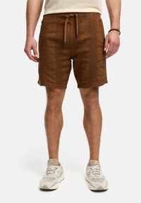 Brune frotté shorts med elastisk talje og snor. Har teksturerede lodrette striber langs siderne og en afslappet pasform.