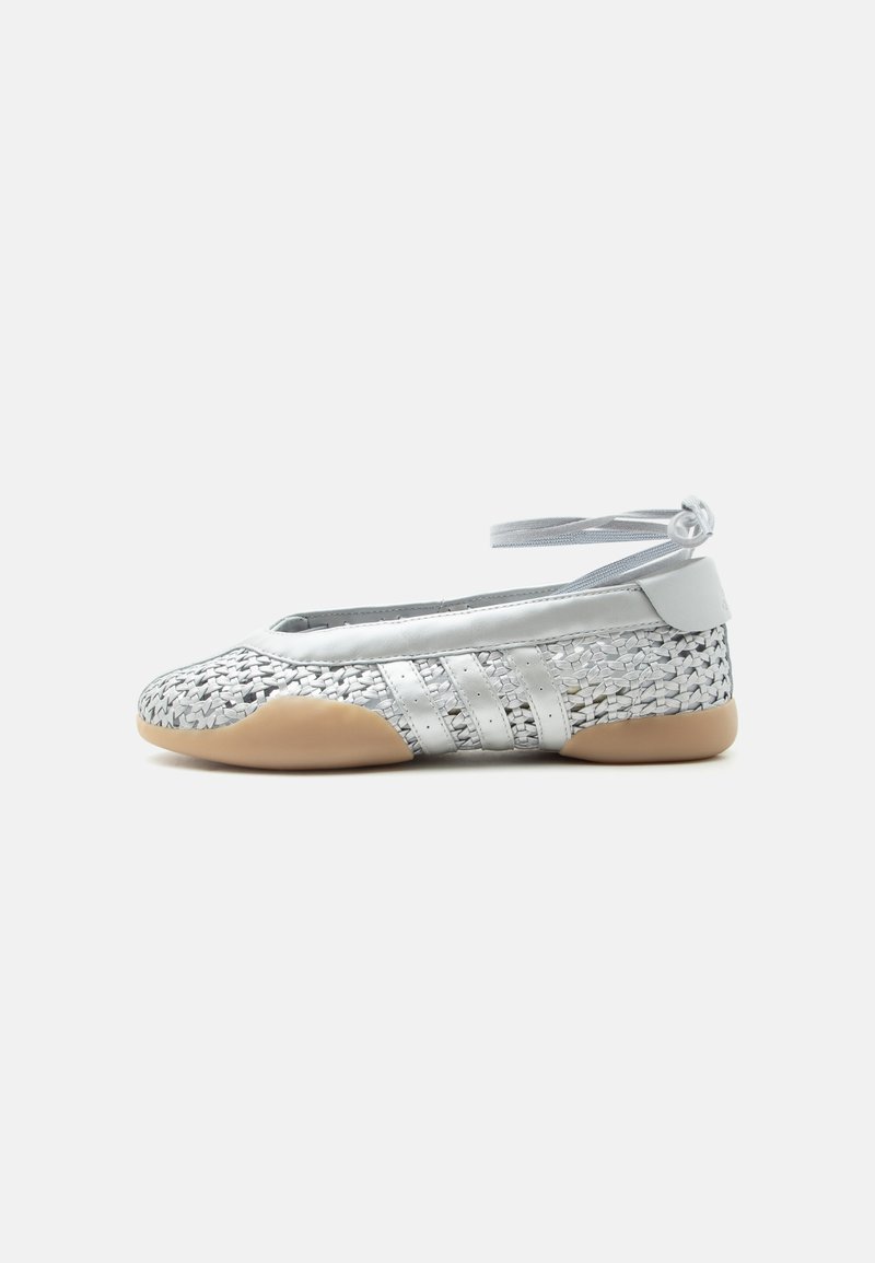 White woven ballet flat with beige sole, three white side stripes, and ankle wrap strap on a plain background.