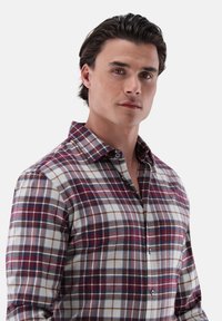 Camicia in cotone a quadri con motivi a check rossi, blu navy e bianchi, colletto button-down e maniche lunghe. Tessuto liscio, vestibilità rilassata.