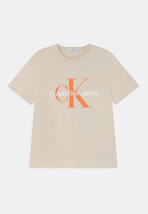 Lyse beige bomuld t-shirt med korte ærmer, med et orange "CK" logo og teksten "Calvin Klein Jeans" i hvid tværs over brystet.
