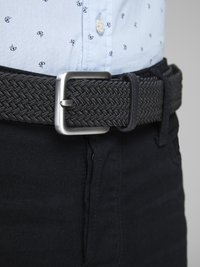 Ceinture tissée noire avec une boucle rectangulaire en métal argenté, portée sur un jean foncé, associée à une chemise à motifs bleu clair.