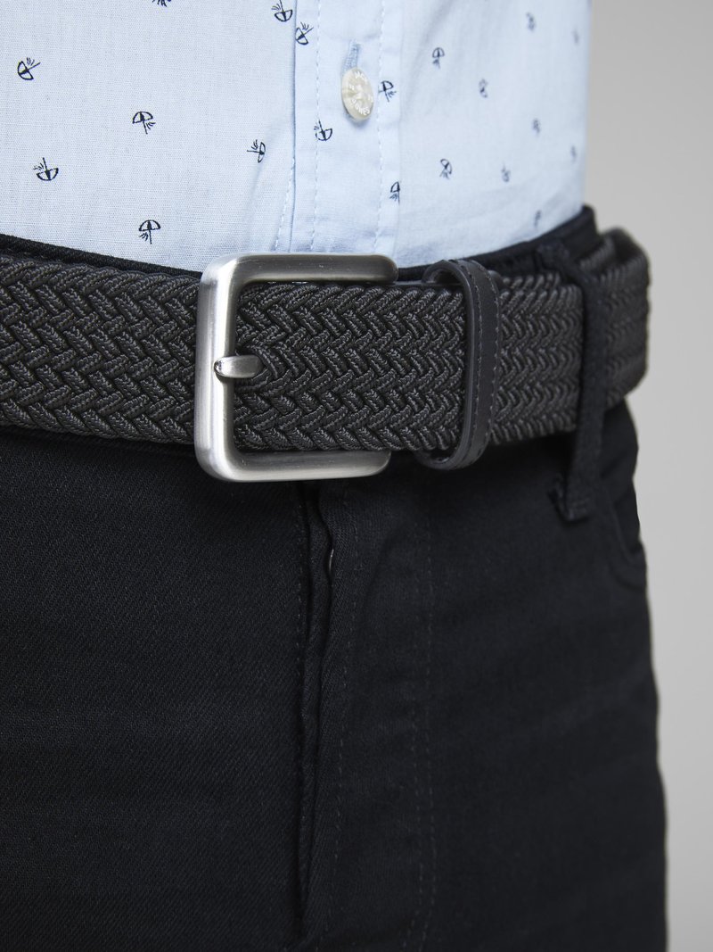 Ceinture tissée noire avec une boucle rectangulaire en métal argenté, portée sur un jean foncé, associée à une chemise à motifs bleu clair.