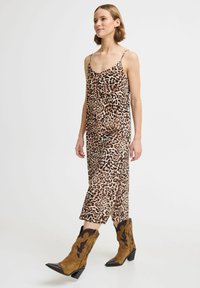 Abito senza maniche con stampa leopardata, dal taglio morbido, con orlo di lunghezza media e spacco laterale, abbinato a stivali da cowboy marroni.