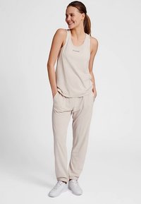 Lichtbeige tanktop en bijpassende broek van zachte stof. De tanktop heeft een ronde halslijn en de broek een elastische tailleband.