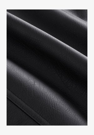 Svart konstläder med en texturerad yta som visar djupa rynkor och veck, vilket framhäver dess flexibla och mjuka karaktär.