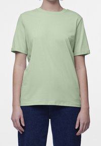 T-shirt verde chiaro a maniche corte realizzato in morbido cotone, con colletto a girocollo e vestibilità comoda. Abbinato a jeans blu scuro.