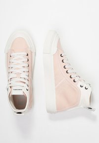 Růžové vysoké plátěné tenisky s bílými tkaničkami a silnými bílými gumovými podrážkami, zobrazené z horního a bočního úhlu na bílém pozadí.