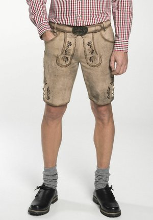 Pantalones cortos de cuero beige con patrones florales bordados, bolsillos frontales y botones metálicos. Combinados con medias grises enrolladas y zapatos negros.