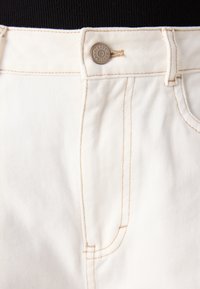 Hvite denim bukser med en teksturert finish, som har kontraststing, metallknapplukking og sidelommer.