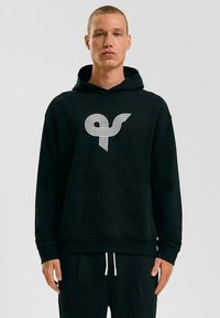 Zwarte hoodie met een witte gestreepte grafische logo op de borst. Gemaakt van zachte materialen met een kangoeroe pocket en geribbelde manchetten.