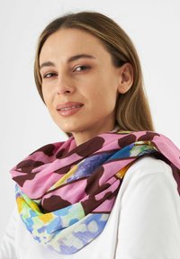 Écharpe multicolore avec une base rose et de grands accents marron et à motifs. Tissu léger qui tombe élégamment autour du cou.