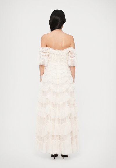 Off-the-shoulder, long white dress with layered ruffles, textured fabric, and sheer puff sleeves. Back zipper with a flowing silhouette.
