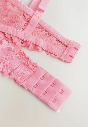 A rózsaszín csipkés melltartópántok fodros széllel, bonyolult mintákkal és puha állítható fémalkatrészekkel rendelkeznek. Az anyag sima és texturált elemeket egyaránt ötvöz.