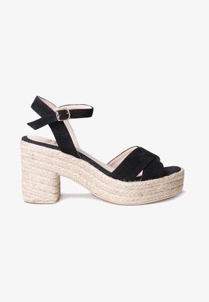 Sandales à plateforme en cuir suédé noir avec une semelle en jute tissée de style espadrille, présentant une bride de cheville avec une boucle métallique.