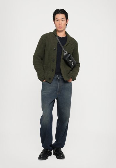 Cardigan tricotat de culoare verde măsliniu cu guler tip șal, închidere cu buton, asortat cu blugi blue denim și încălțăminte neagră. Geantă mică neagră tip crossbody.