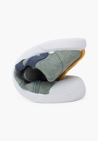 Sneaker pieghevole con suola in gomma bianca. Presenta una tomaia in tessuto verde, grigio e blu navy, dettagli testurizzati e un pezzo sul tallone giallo.