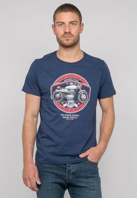 T-shirt bleu marine en coton, avec un graphique de moto vintage en rouge et blanc, col rond et manches courtes.