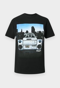 Melns T-krekls ar grafiku, kurā attēlots boombox ar caurspīdīgu panteru, fons ir pilsētas panorāma.