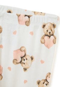 Tissu de pyjama en coton présentant un fond bleu clair avec des illustrations répétées d'ours tenant des cœurs roses et de petits motifs de cœurs roses.
