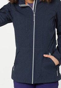 Giacca blu navy a maniche lunghe con zip argentate e due tasche laterali. Presenta un colletto alto e un tessuto leggermente testurizzato.